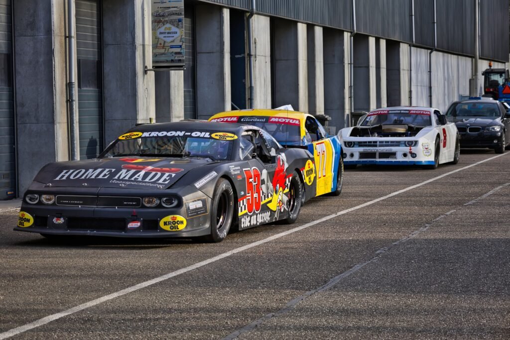 A row of colorful stock cars lined up in a racing garage, ready for motorsport action.
